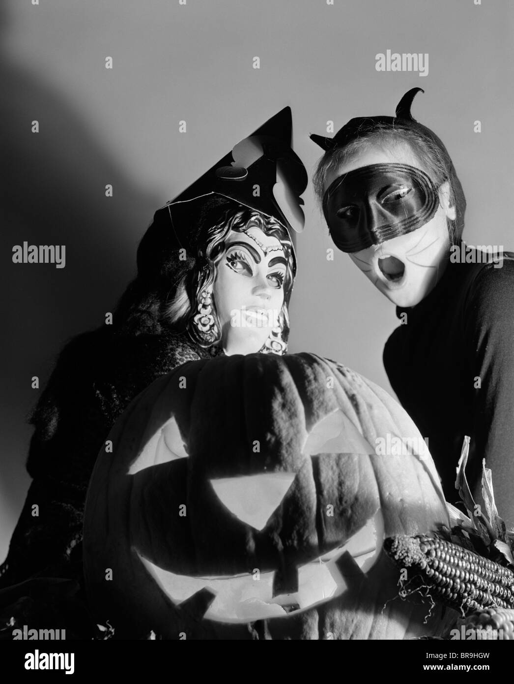 Anni Cinquanta DUE BAMBINI IN COSTUME DI HALLOWEEN dietro una zucca intagliata Jack-O-Lantern Foto Stock
