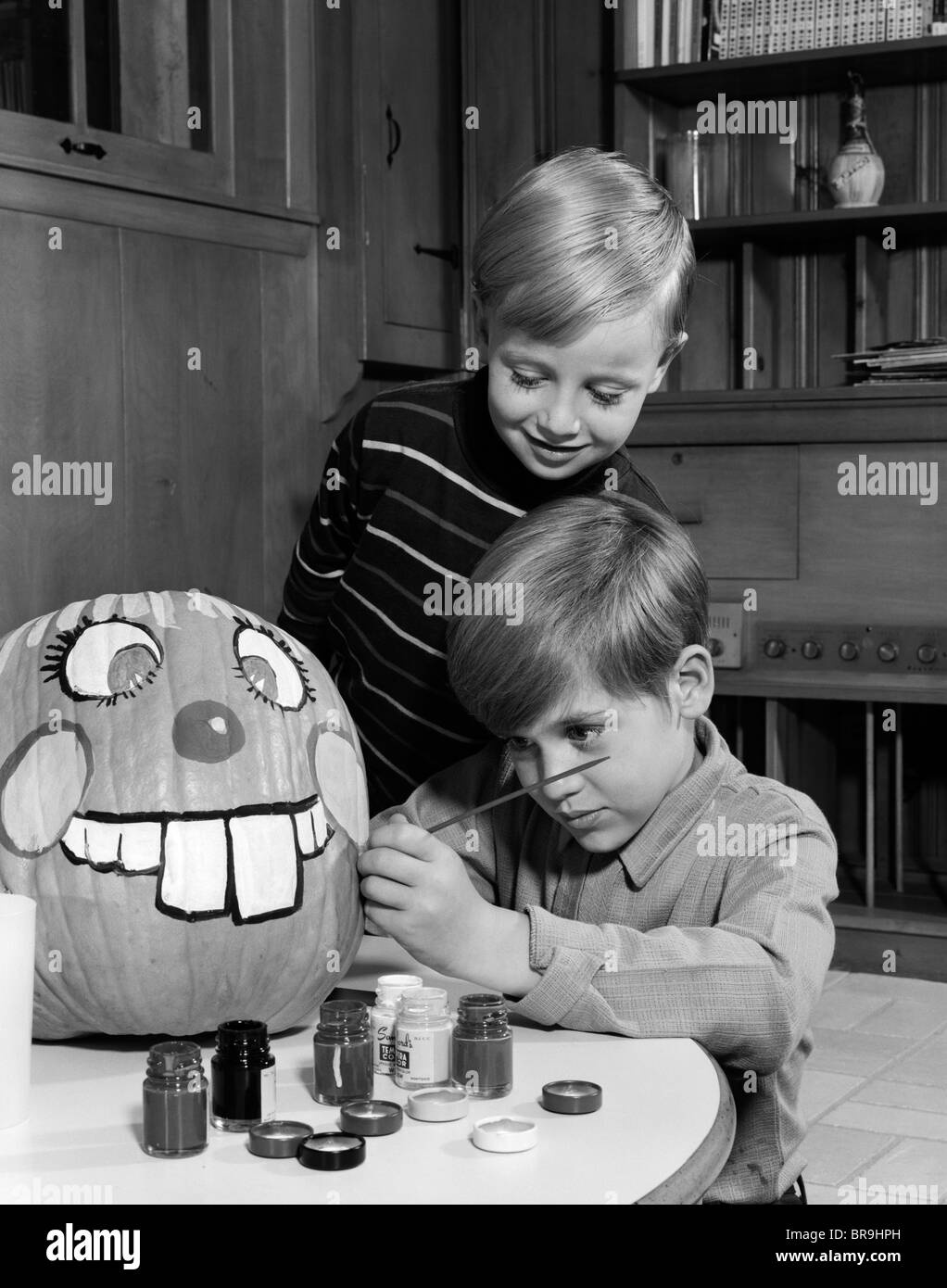 Anni sessanta due ragazzi fratelli pittura Jack-O-Lantern faccia sulla zucca Foto Stock