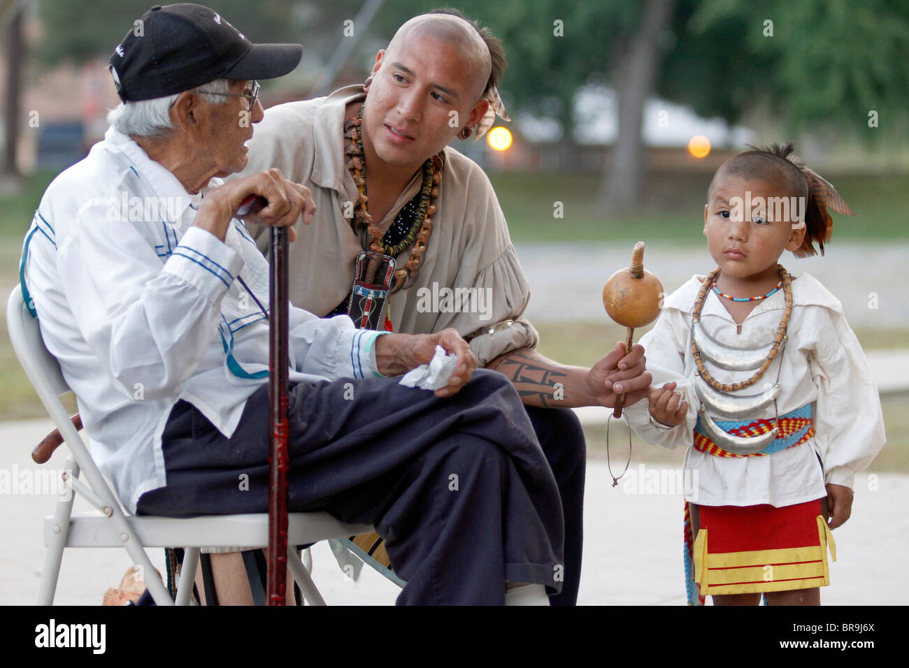 Cherokee, NC- un uomo Cherokee, membro dei guerrieri del gruppo AniKituhwa, accompagnato dal suo figlio, colloqui con un anziano. Foto Stock