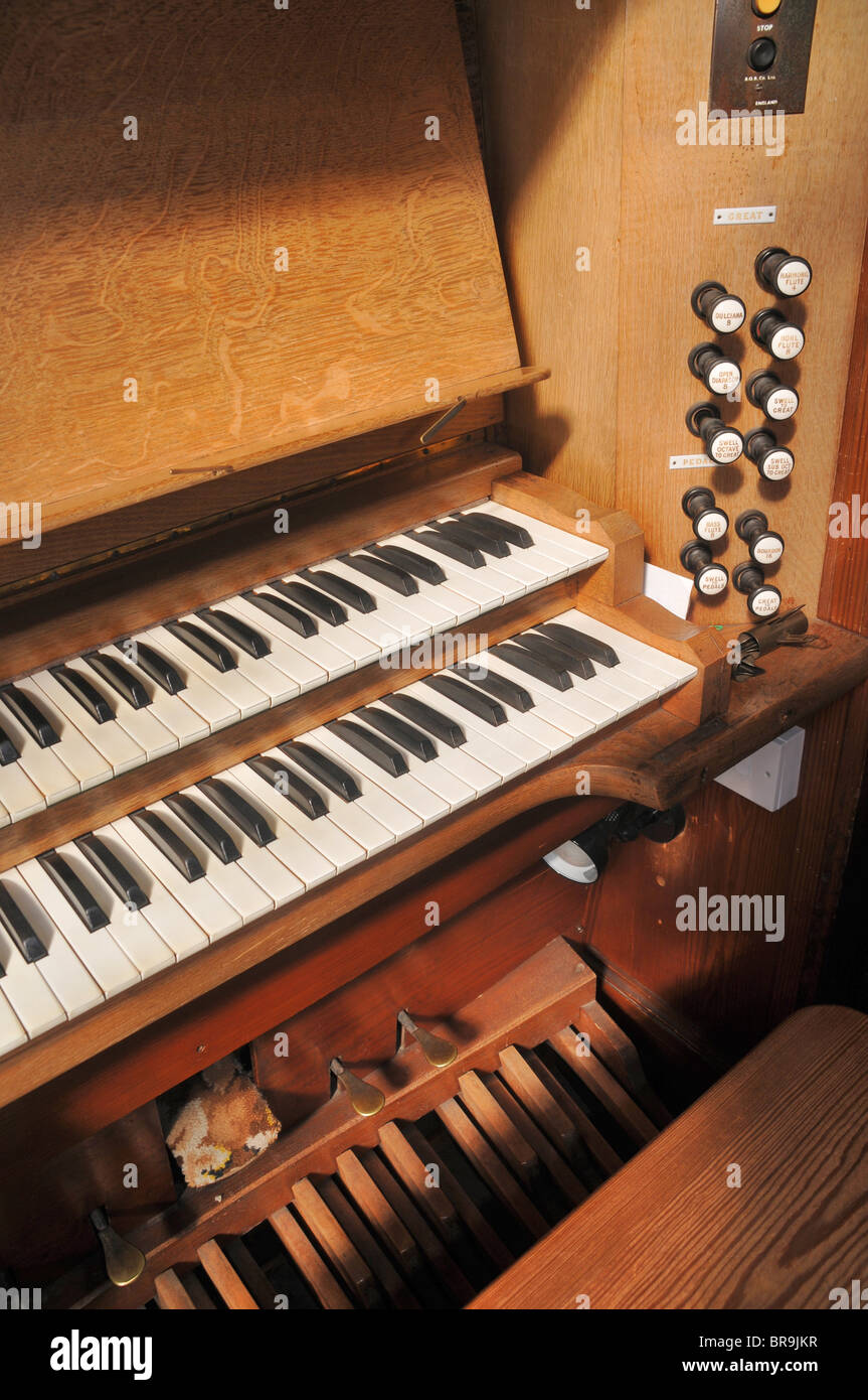 Una vista laterale di una chiesa organo a canne che mostra due tastiere, i pedali e si arresta. Foto Stock