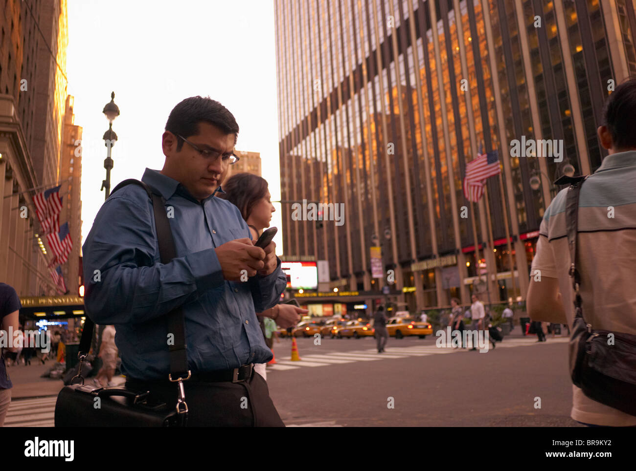 Uomo in camicia blu operando dispositivo tenuto manualmente mentre si sta in piedi sul marciapiede. Foto Stock
