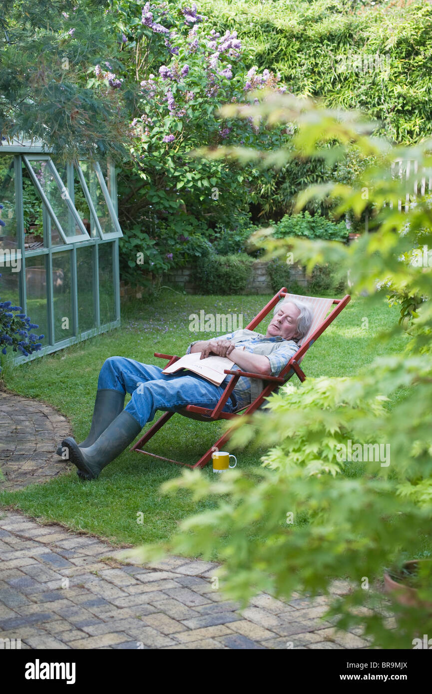 Giardiniere dorme sulla sedia a sdraio nel giardino sul retro Foto Stock
