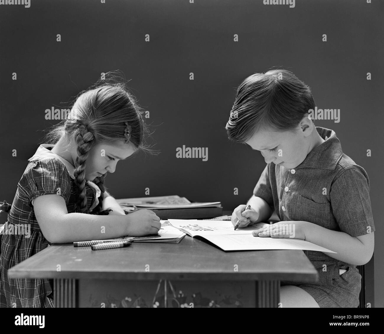 1940s un ragazzo e una ragazza la colorazione nel libro seduti a tavola Foto Stock