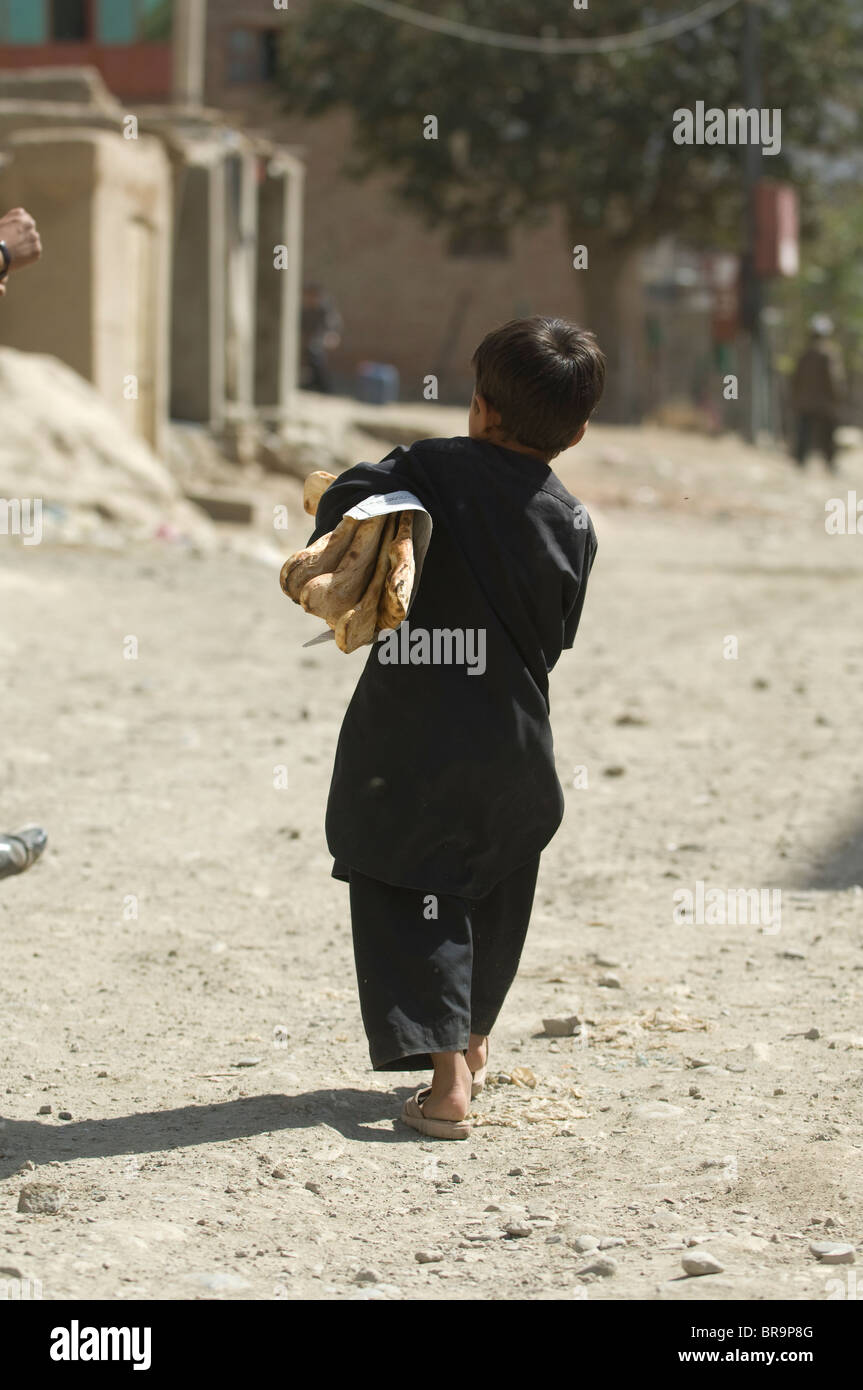 Ragazzo afghano che trasportano il pane piatto a casa dal panificio a Kabul, Afghanistan Foto Stock