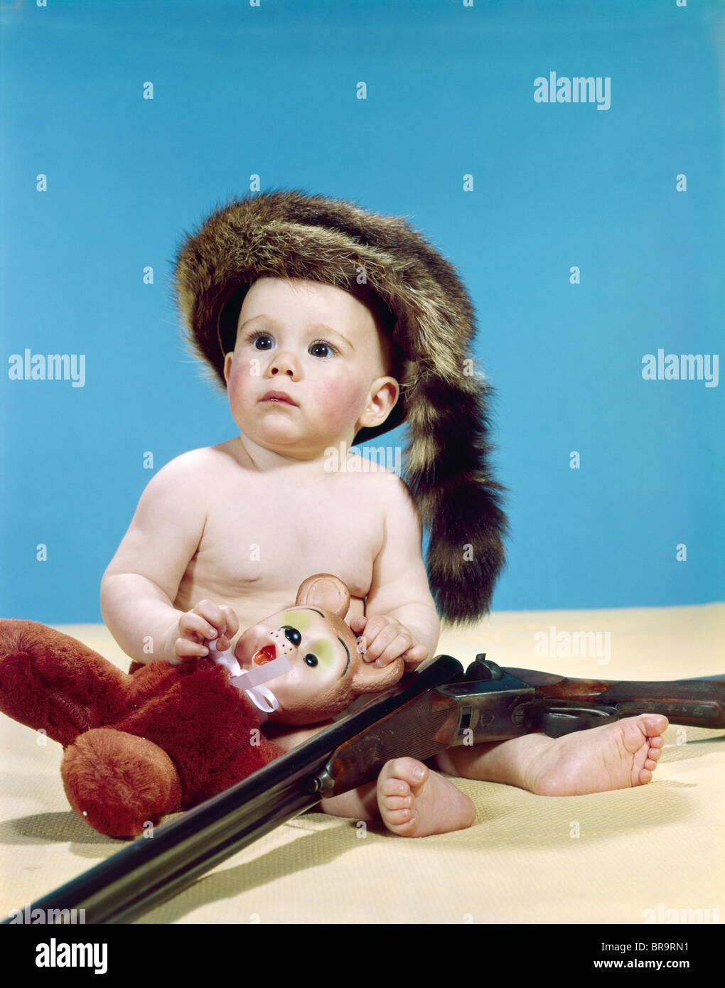 Anni sessanta baby boy indossando COONSKIN CAP con animali impagliati e pistola SHOTGUN Foto Stock