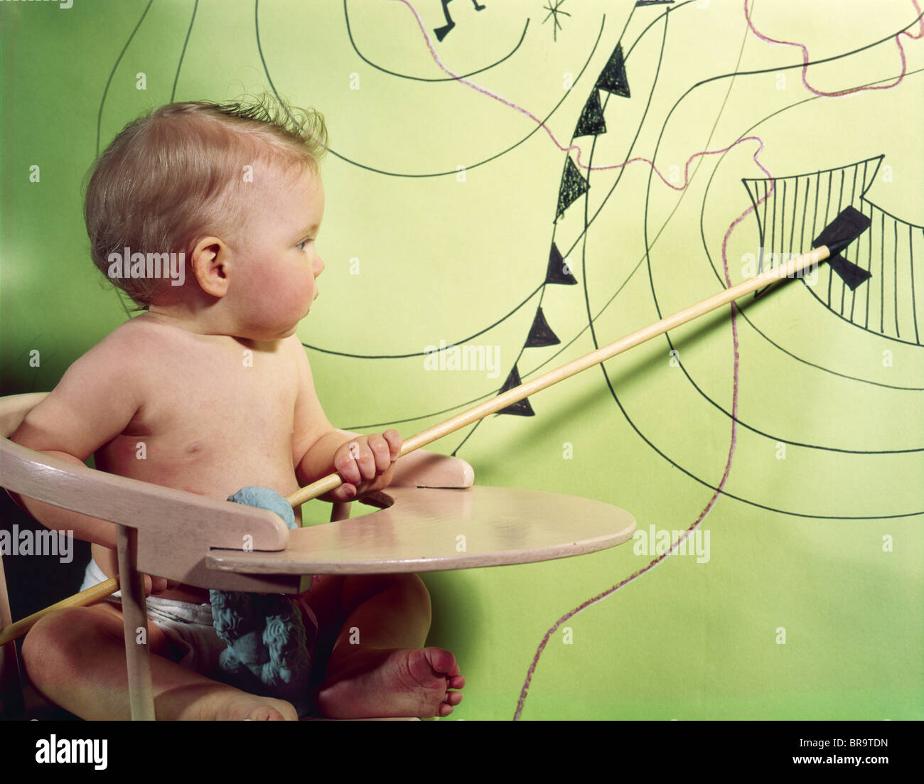 Anni sessanta BABY in sedia alta utilizzando il puntatore in legno per indicare l'area di bassa pressione sulla mappa meteo Foto Stock
