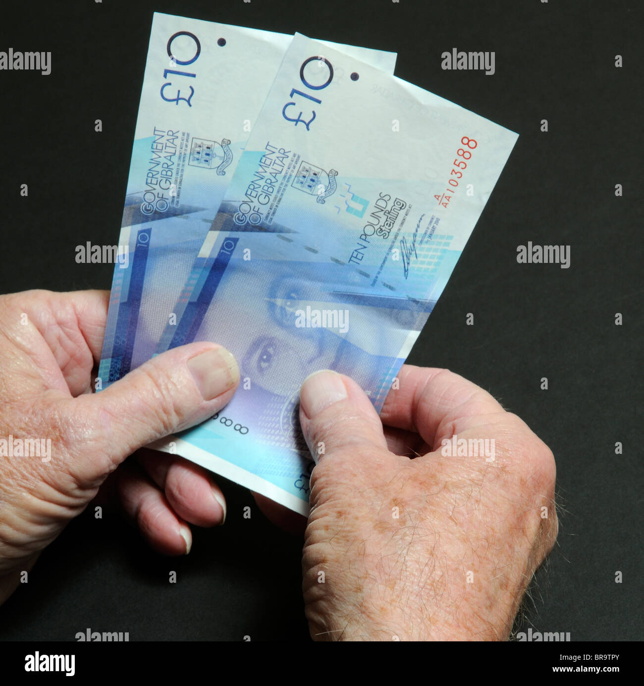 Uomo anziano le mani tenendo il governo di Gibilterra dieci pound note Foto Stock