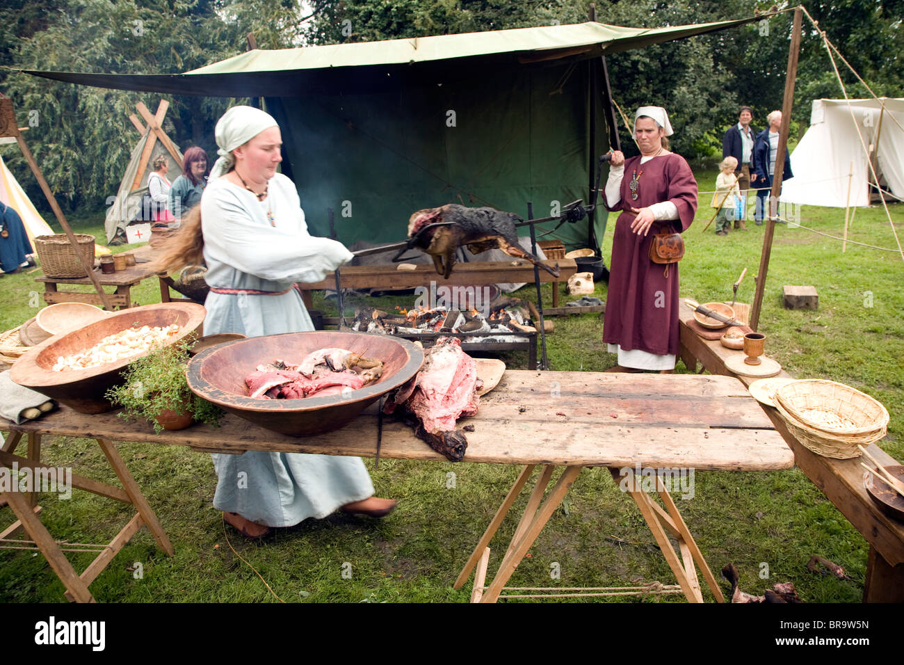 Le donne portano il cervo cotto dal fuoco alla tavola, rievocazione storica Saxon, Viking, Norman storia, Woodbridge, Suffolk Foto Stock