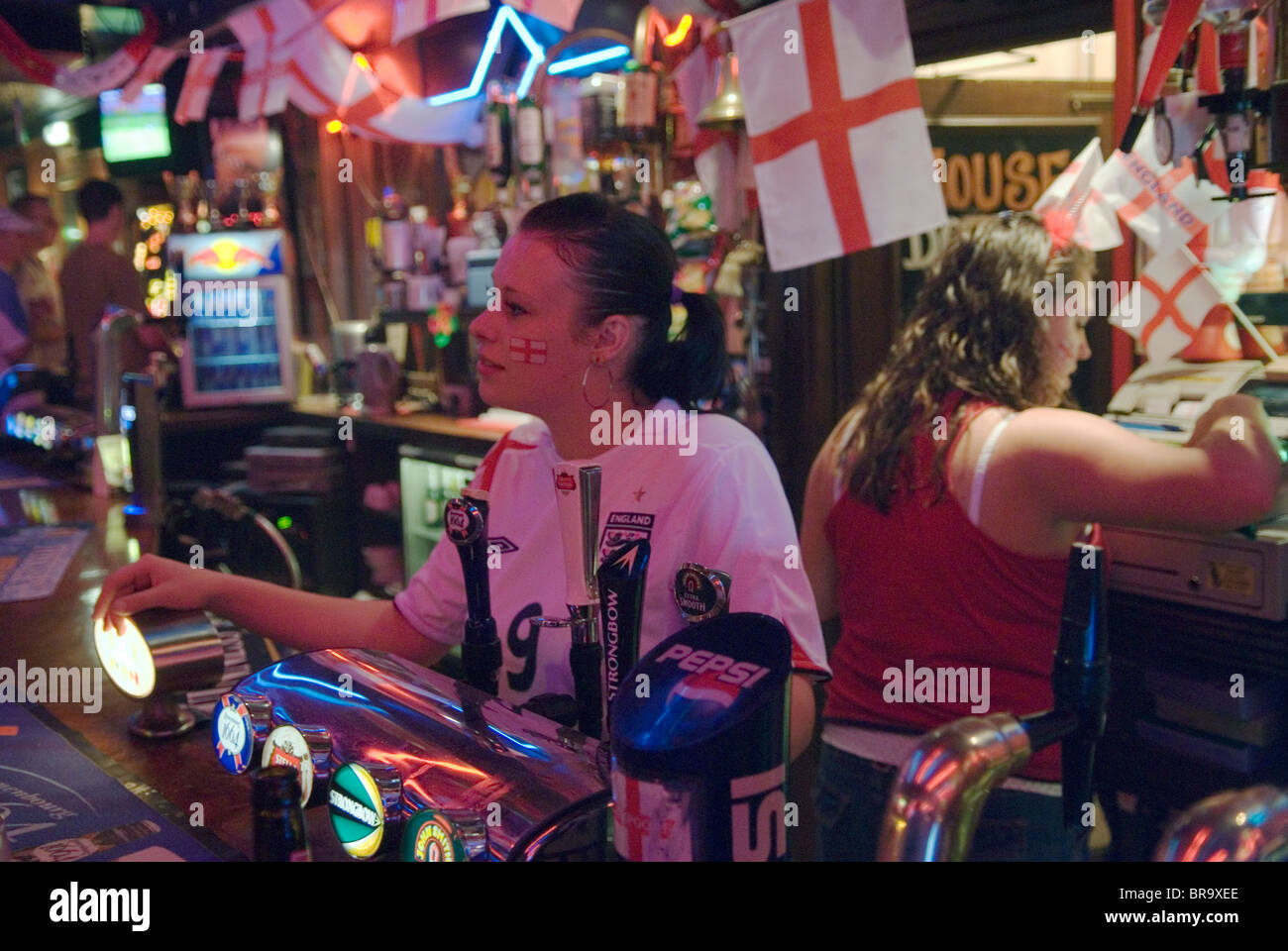 Pub interno donne tirando pinte di birra, interni decorati con inglese union jack flag celebrando la Coppa del Mondo di calcio match 2006 2000s HOMER SYKES Foto Stock
