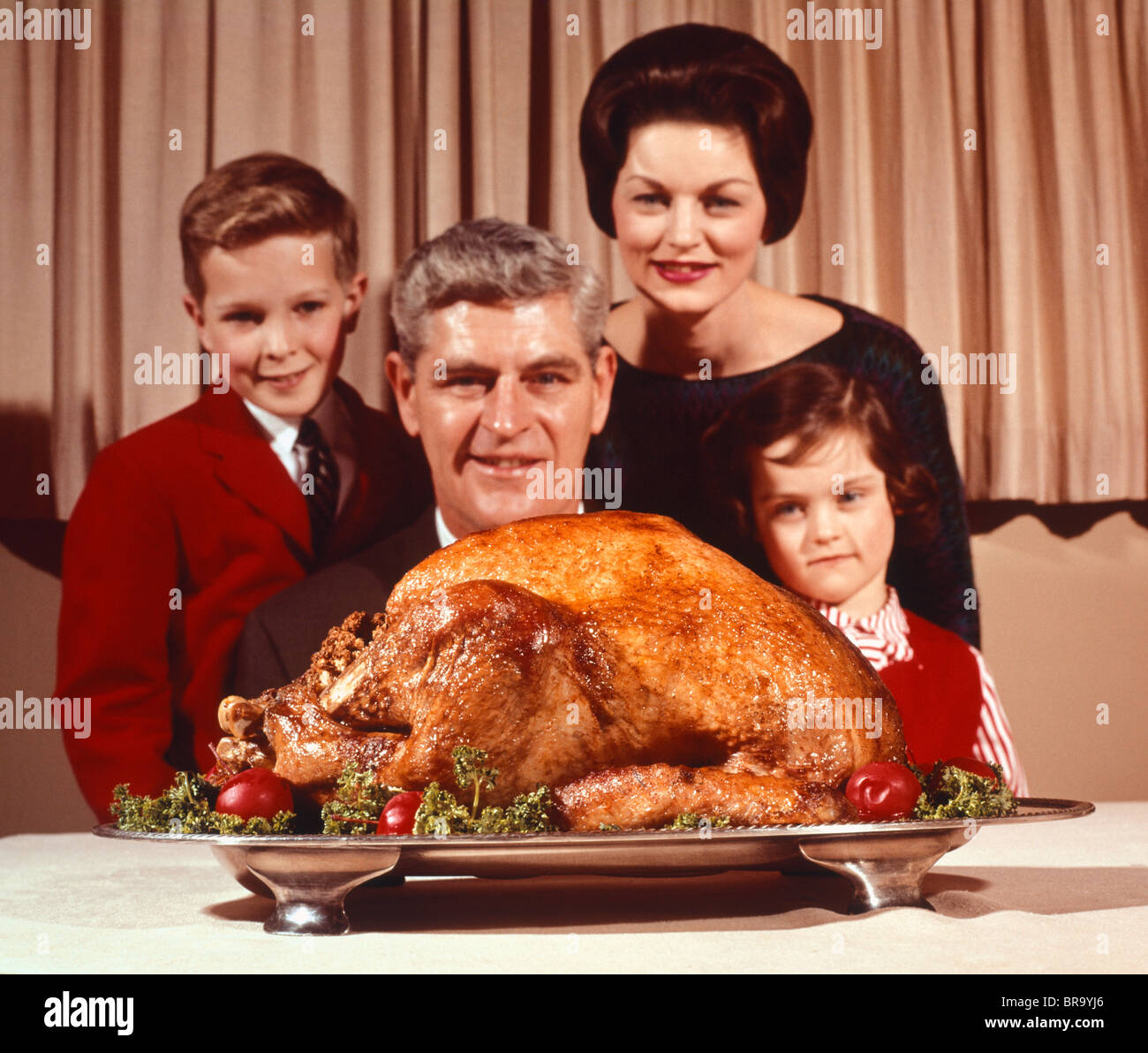 Anni sessanta RITRATTO DI PADRE DI FAMIGLIA madre figlio figlia guardando il giorno del Ringraziamento o di natale il tacchino arrosto Foto Stock