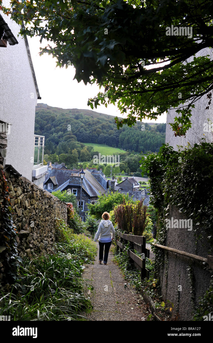 Donna che cammina verso il basso passi nel distretto del Lago Città di Ambleside Cumbria Regno Unito Foto Stock