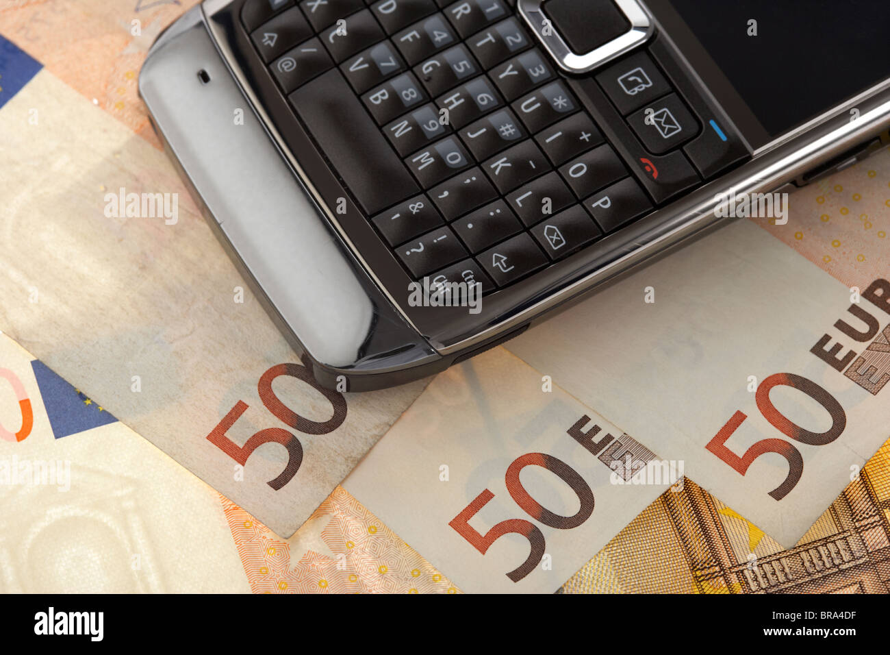 Telefono cellulare smartphone su un palo di 50 banconote in euro Foto Stock