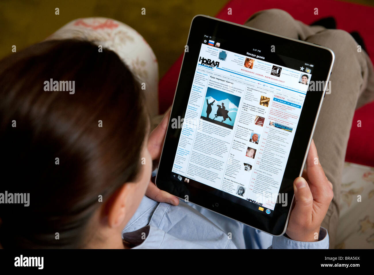 Donna che utilizza computer tablet iPad a casa per leggere il russo Novaya Gazeta giornale Foto Stock