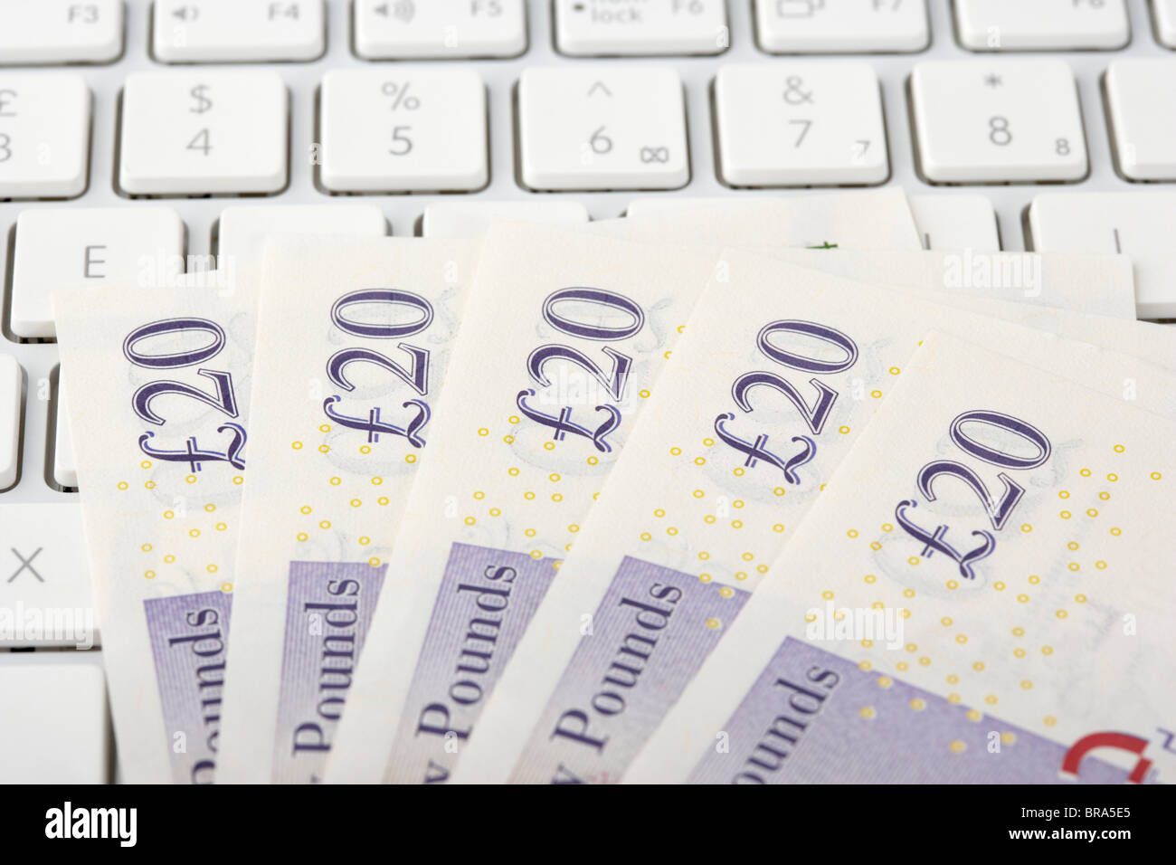 Pila di venti sterline banconote sulla tastiera di un computer Foto Stock