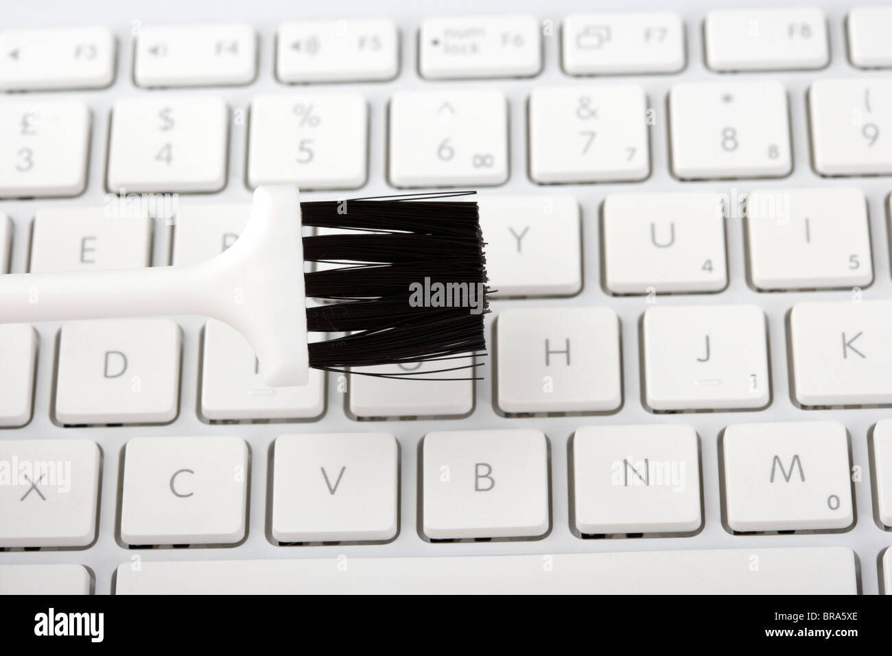 La pulizia di un computer portatile tastiera con una piccola spazzola in plastica Foto Stock