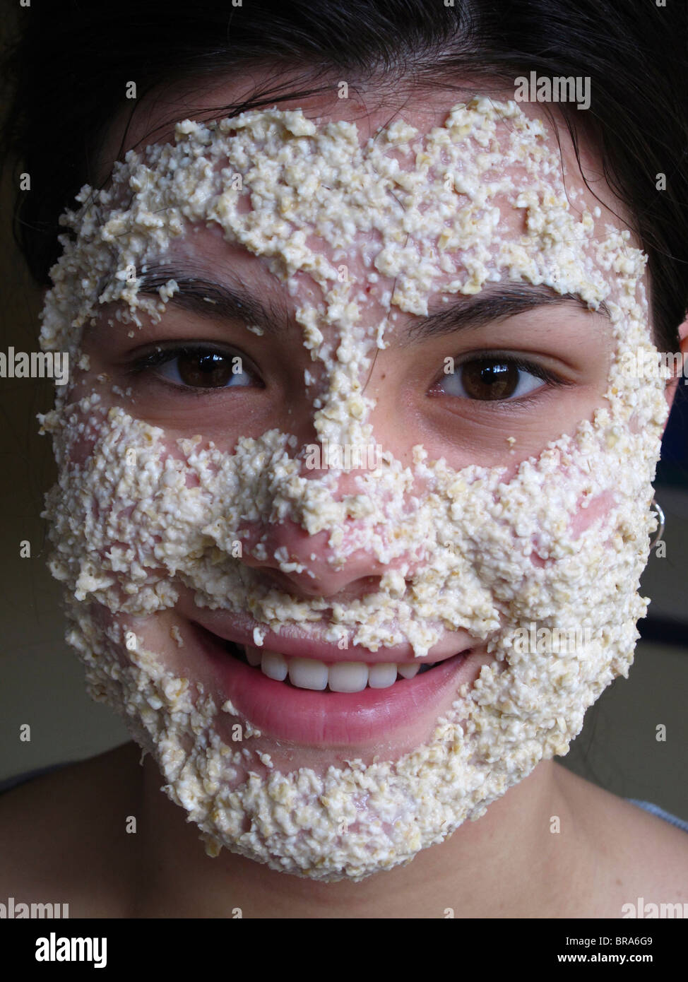 Ragazza adolescente utilizzando una maschera di avena per ripulire la sua pelle Foto Stock