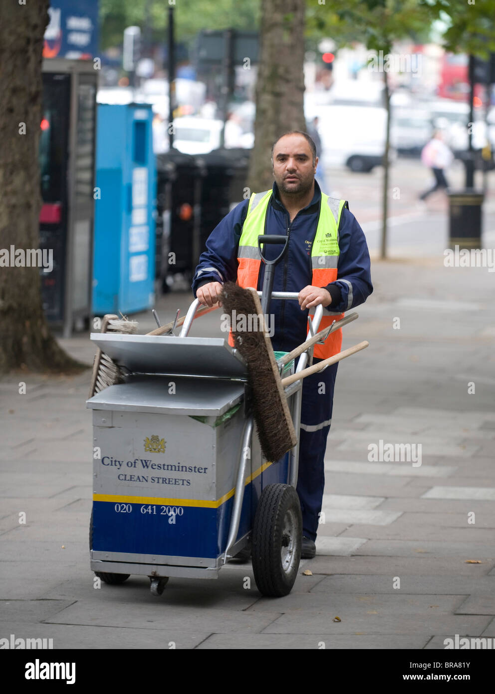 Westminster street sweeper spinge il suo barrow e Ginestra Foto Stock