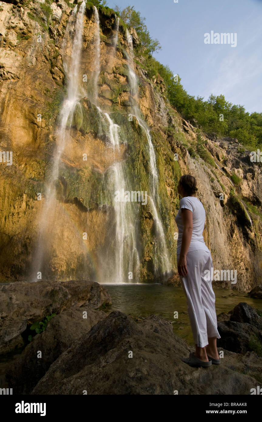 Donna che guarda ad una cascata gigantesca, il Parco Nazionale dei Laghi di Plitvice, patrimonio mondiale dell UNESCO, Croazia, Europa Foto Stock