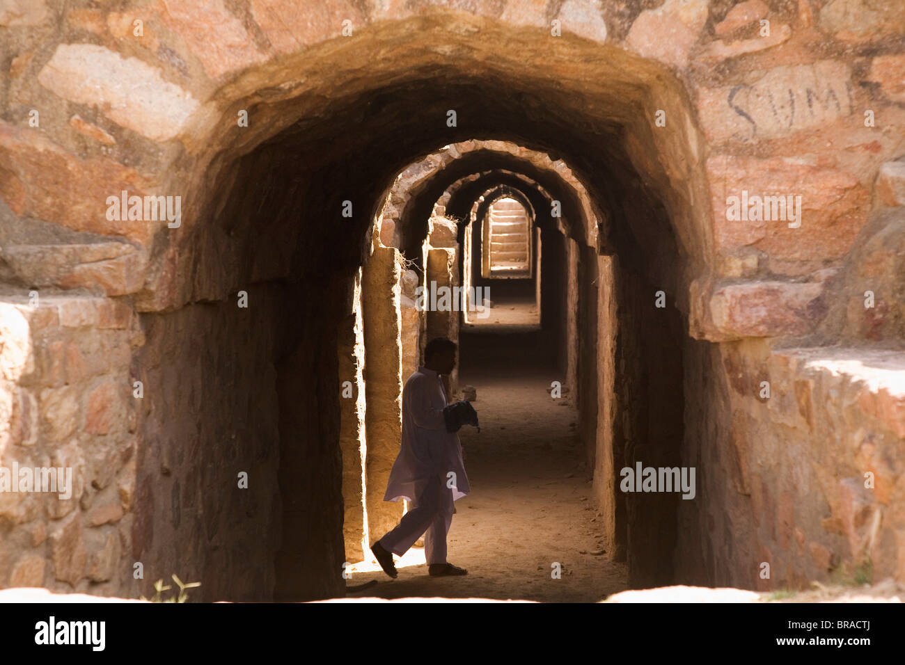 Un uomo indiano in visita nei sotterranei della Rocca Tughluqabad, Delhi, India Foto Stock