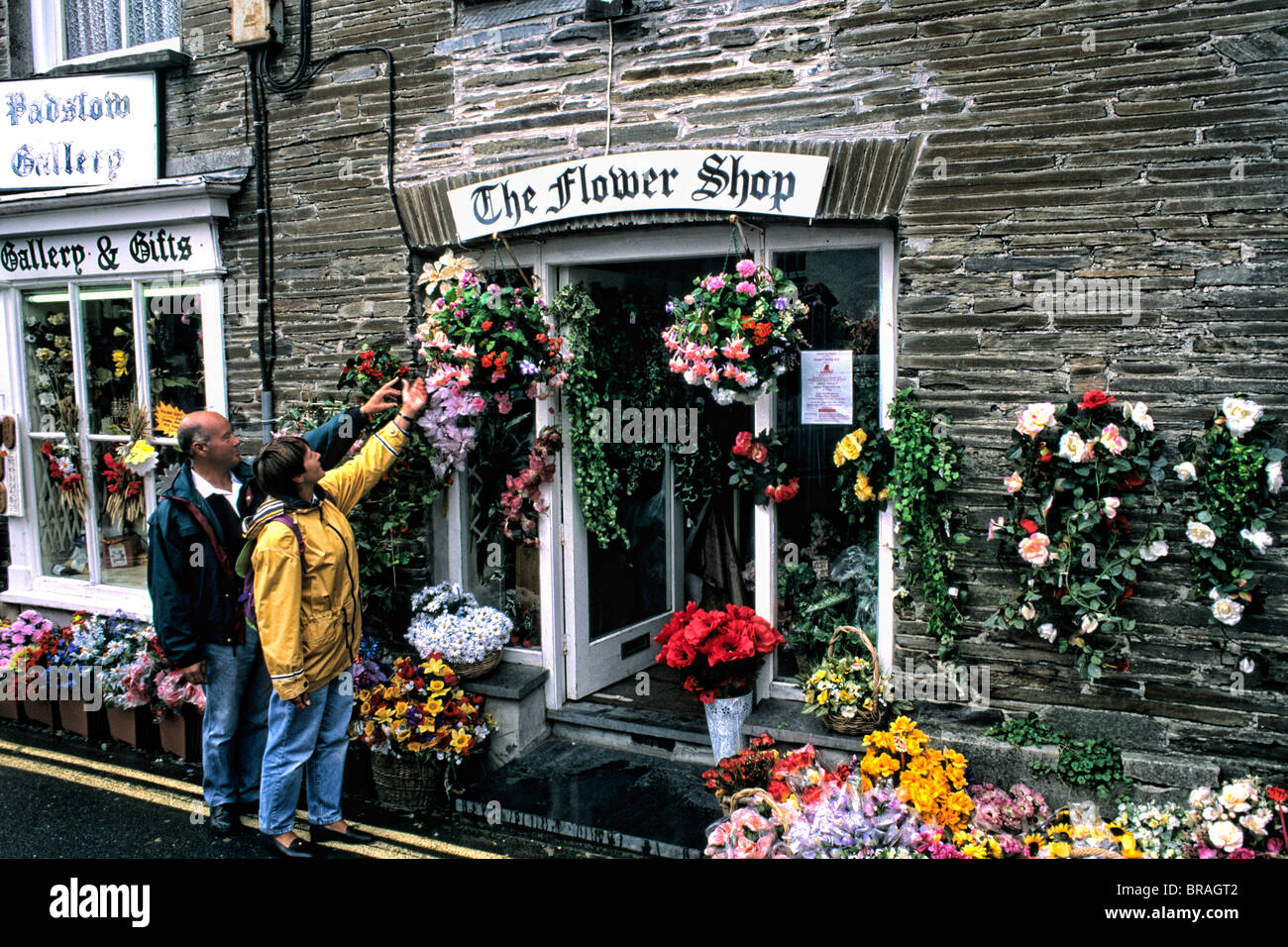 Fiori colorati in negozio con i turisti in Cornwall Inghilterra Foto Stock