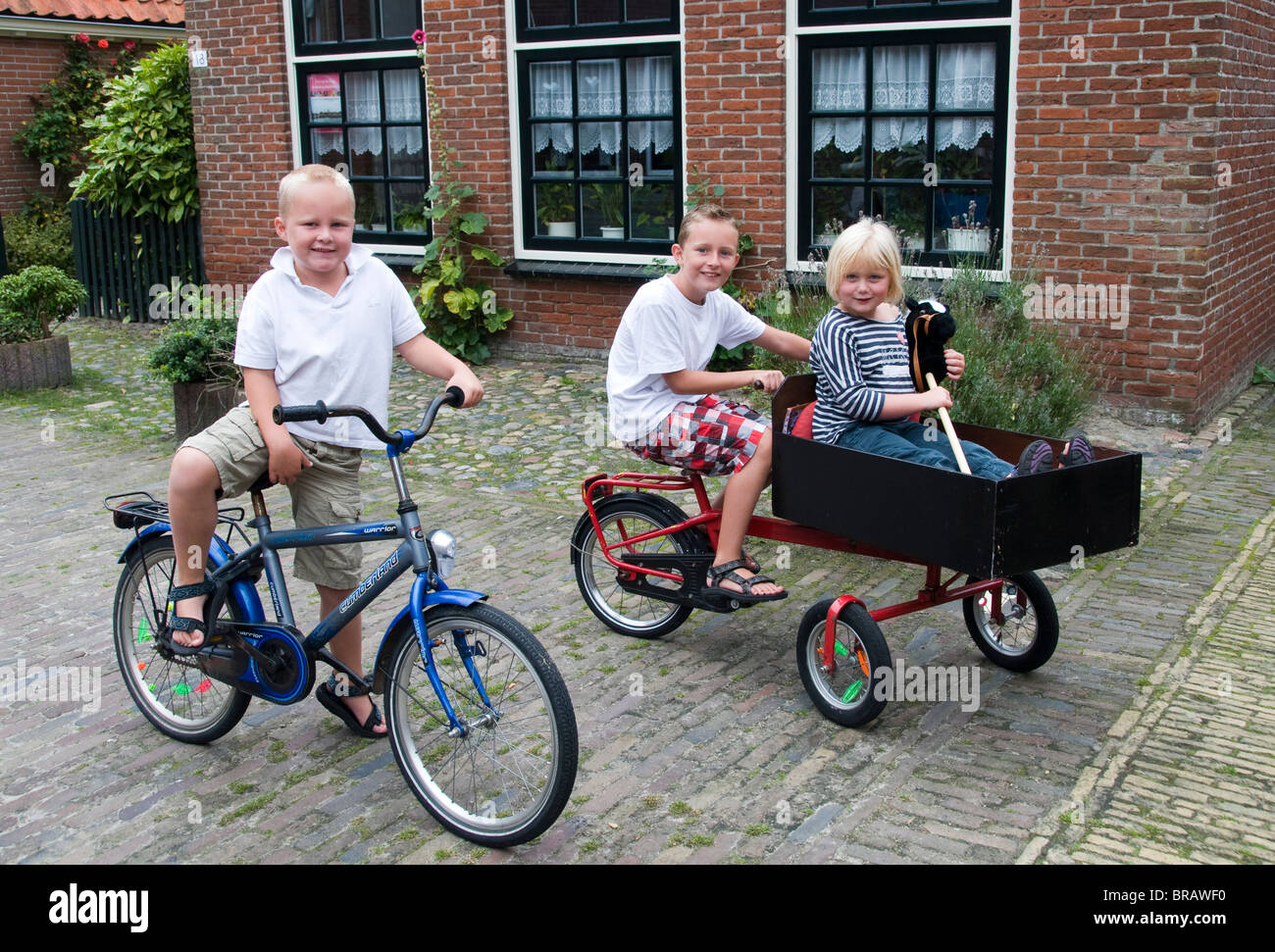 Frisia Hindeloopen boy ragazze biciclette giocare divertimento bambini IJsselmeer Fryslan Paesi Bassi Foto Stock