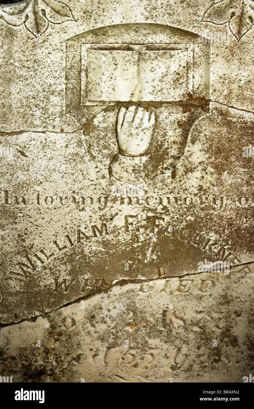 Dettaglio di una vecchia lastra tombale che mostra una mano rivolta verso il cielo e un libro aperto Foto Stock