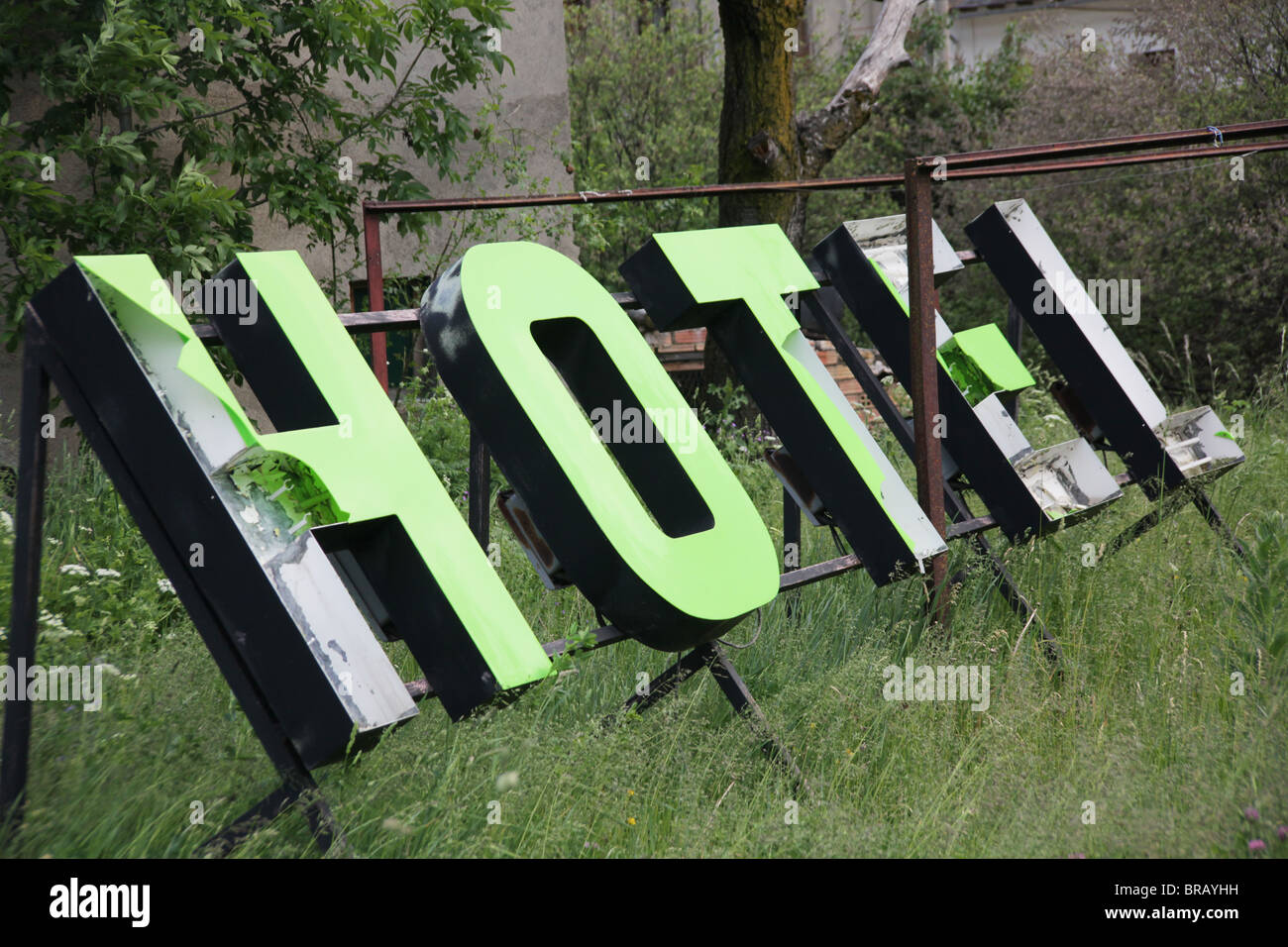 Chiuso-down neon rotto hotel elettrico segno si fermò gettati in un giardino Foto Stock