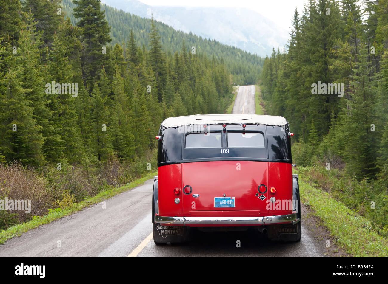 Bus rosso sulla strada da Cameron Lake, il Parco Nazionale dei laghi di Waterton, Alberta, Canada. Foto Stock