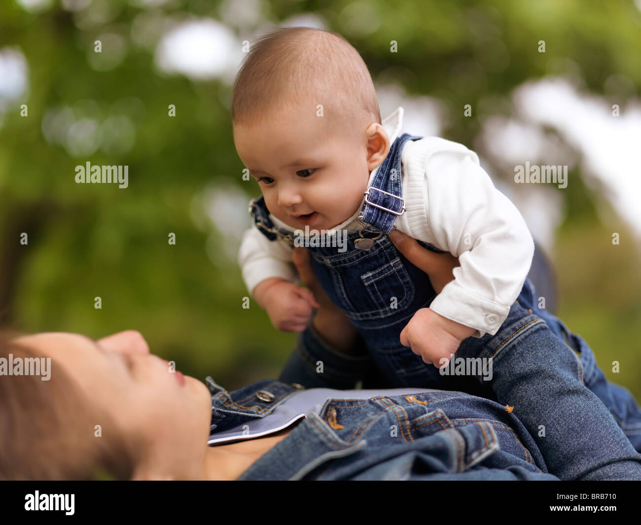 Madre giocando con una felice sorridente bambina di quattro mesi boy nella natura Foto Stock