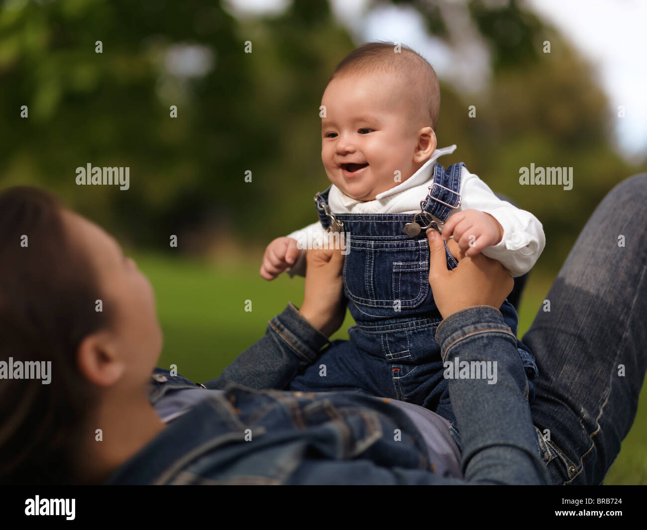 Madre giocando con una felice sorridente bambina di quattro mesi boy nella natura Foto Stock