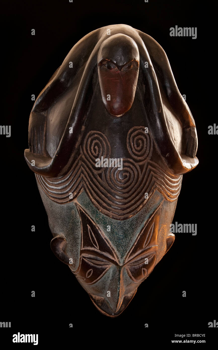 Legno scolpito tribale africana maschera, riprese dall'alto, legno scuro con faccia dipinta, animale sulla testa che mostra i denti. Africa, Foto Stock