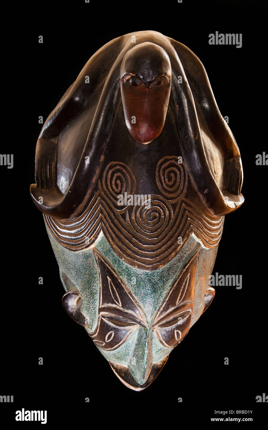 Legno scolpito tribale africana maschera, riprese dall'alto, legno scuro con faccia dipinta, animale sulla testa che mostra i denti. Africa, Foto Stock