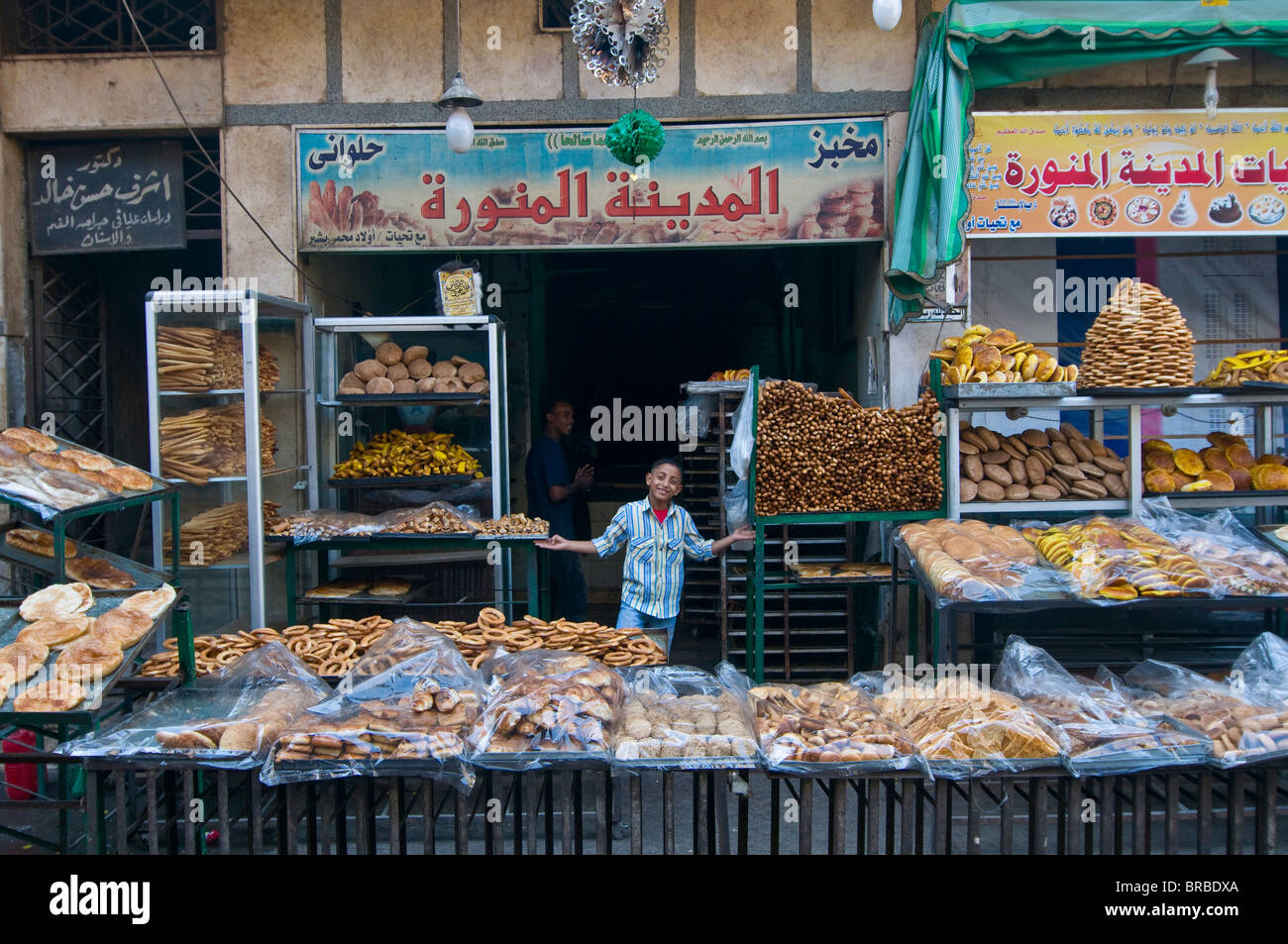 Ragazzo giovane la vendita di pane fresco in una panetteria nella parte vecchia del Cairo, Egitto, Nord Africa Foto Stock