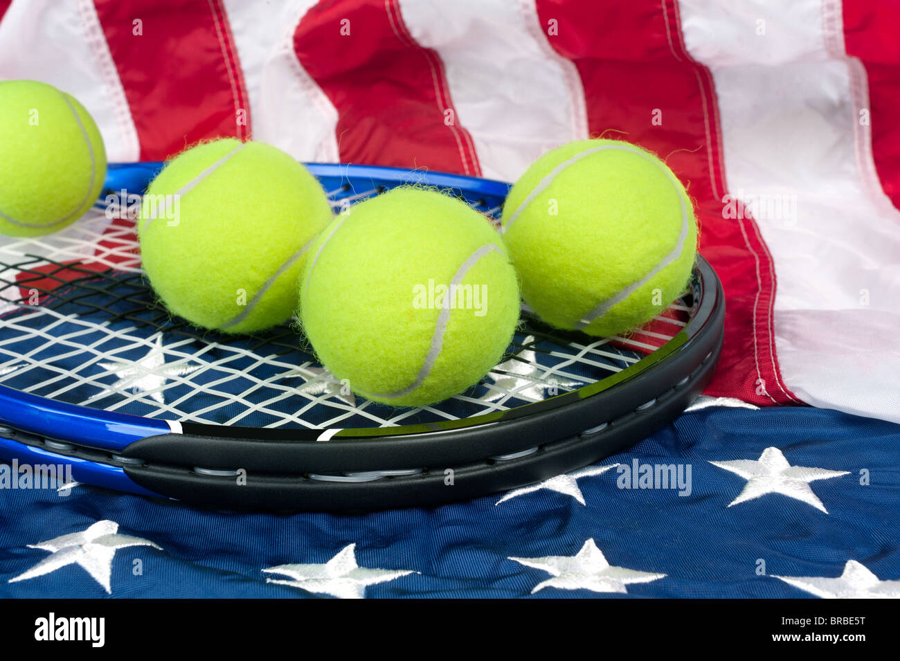 Una racchetta da tennis con nuove palline da tennis su una bandiera americana Foto Stock