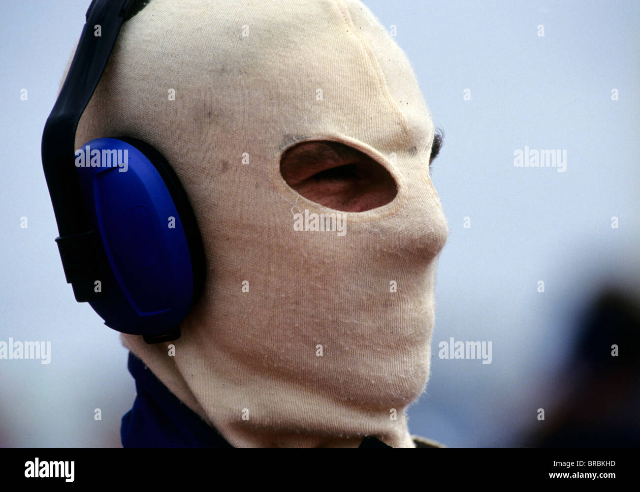 Uomo che indossa una maschera ignifuga e cuffie a drag racing via Foto Stock