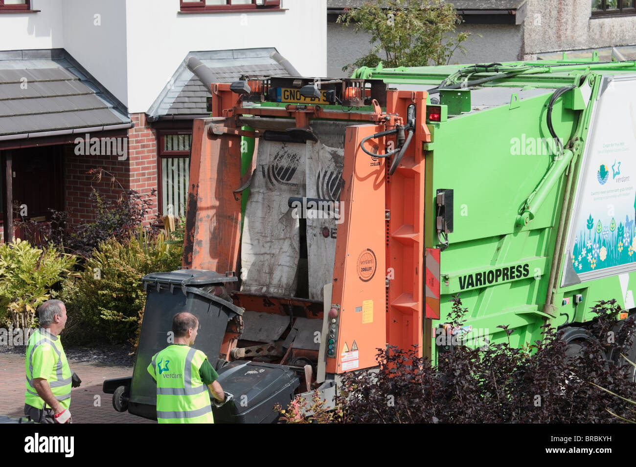 Gli uomini lo scomparto di raccolta di rifiuti domestici di caricamento scomparti wheelie sul camion della spazzatura in strada. Anglesey North Wales, Regno Unito, Gran Bretagna. Foto Stock Gli uomini lo scomparto di raccolta di rifiuti domestici di caricamento scomparti wheelie sul camion della spazzatura in strada. Anglesey North Wales, Regno Unito, Gran Bretagna. Foto Stock