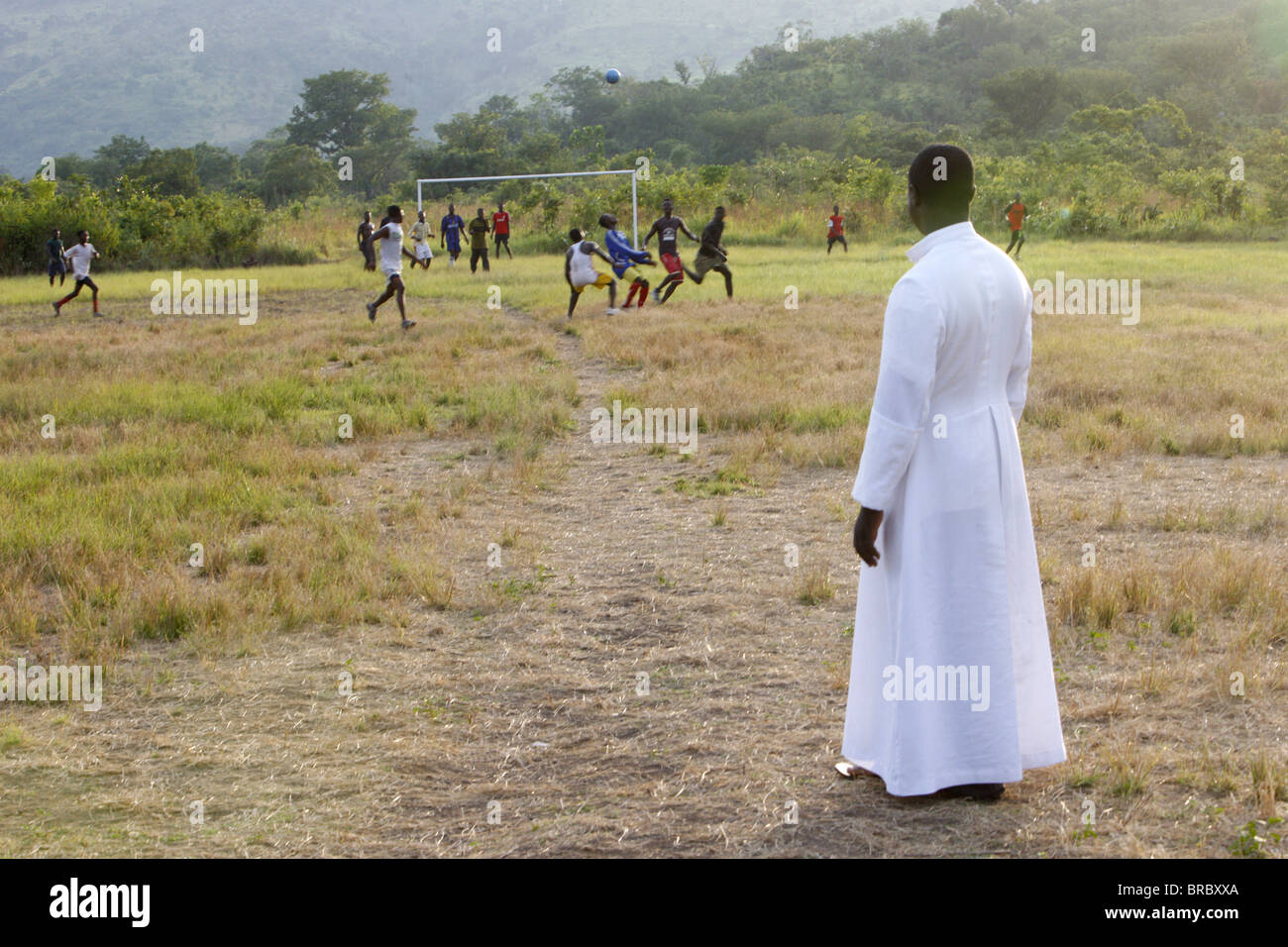 Sacerdote cattolico a guardare una partita di calcio, Akata Djokpe, Togo, Africa occidentale Foto Stock