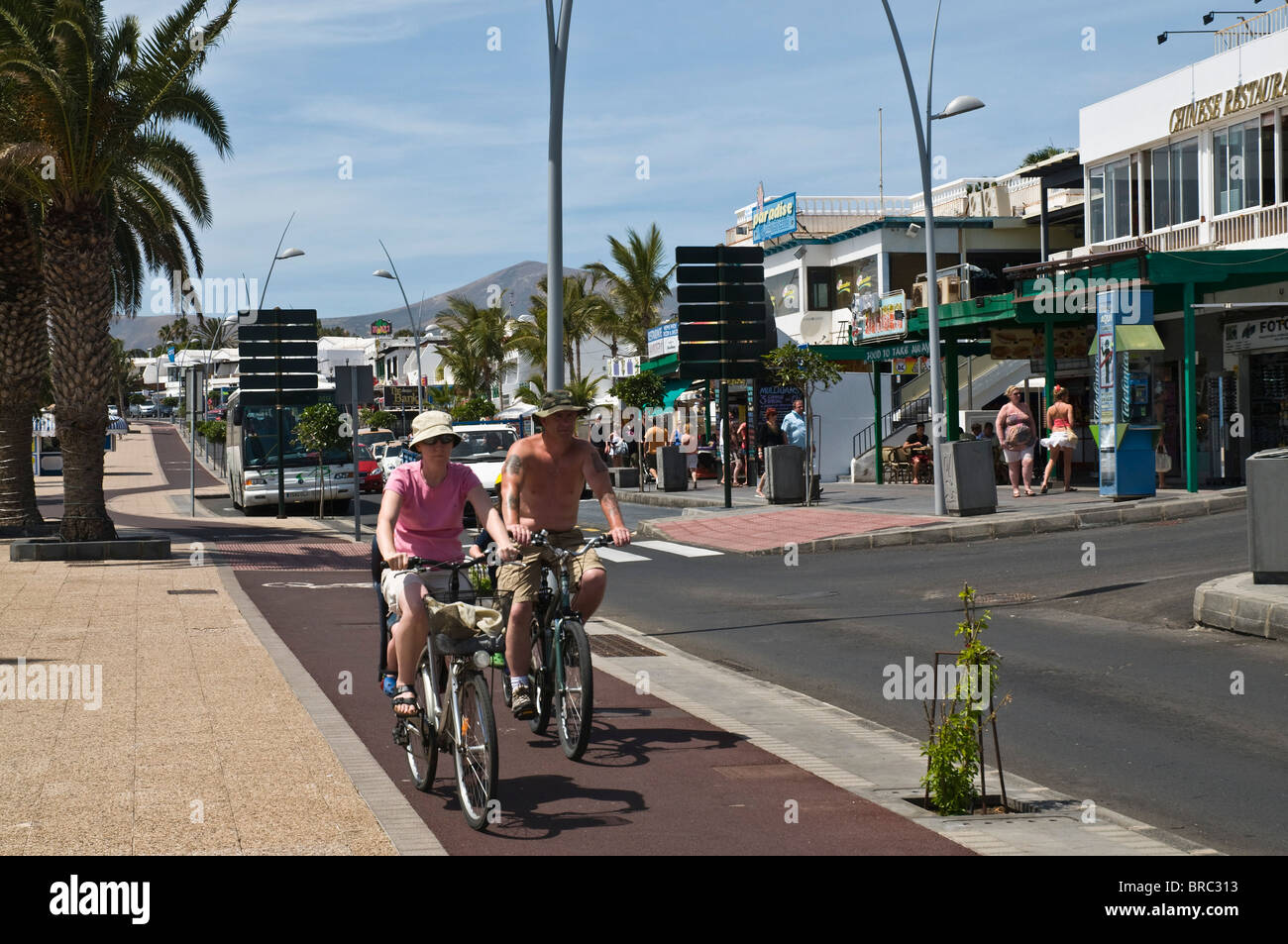 Dh PUERTO DEL CARMEN LANZAROTE turista giovane ciclisti sulla pushbikes percorso ciclabile marciapiede Foto Stock