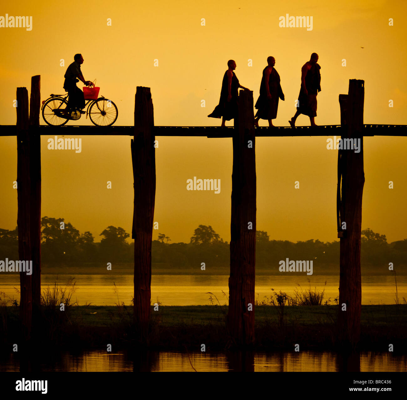 Tre monaci e una bici in cima al ponte Ubein al tramonto Foto Stock