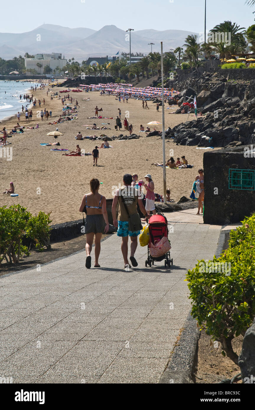 Dh Spiaggia Puerto del Carmen LANZAROTE turista giovane passeggino camminando giù alla spiaggia vacanze ragazzi vacanze in famiglia Foto Stock