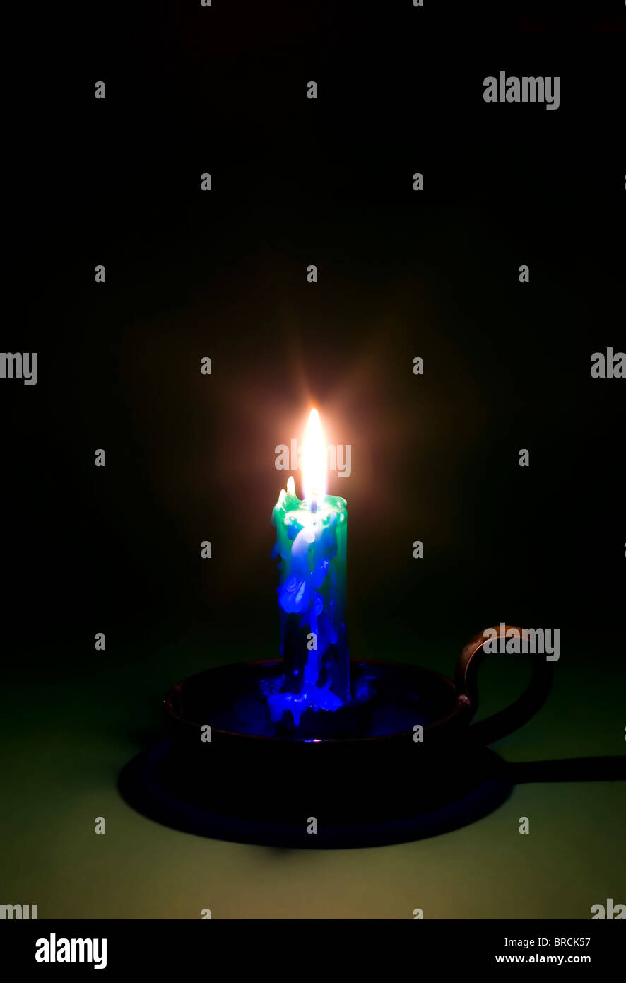 Vi è una fiammante candela sul verde scuro dello sfondo Foto Stock