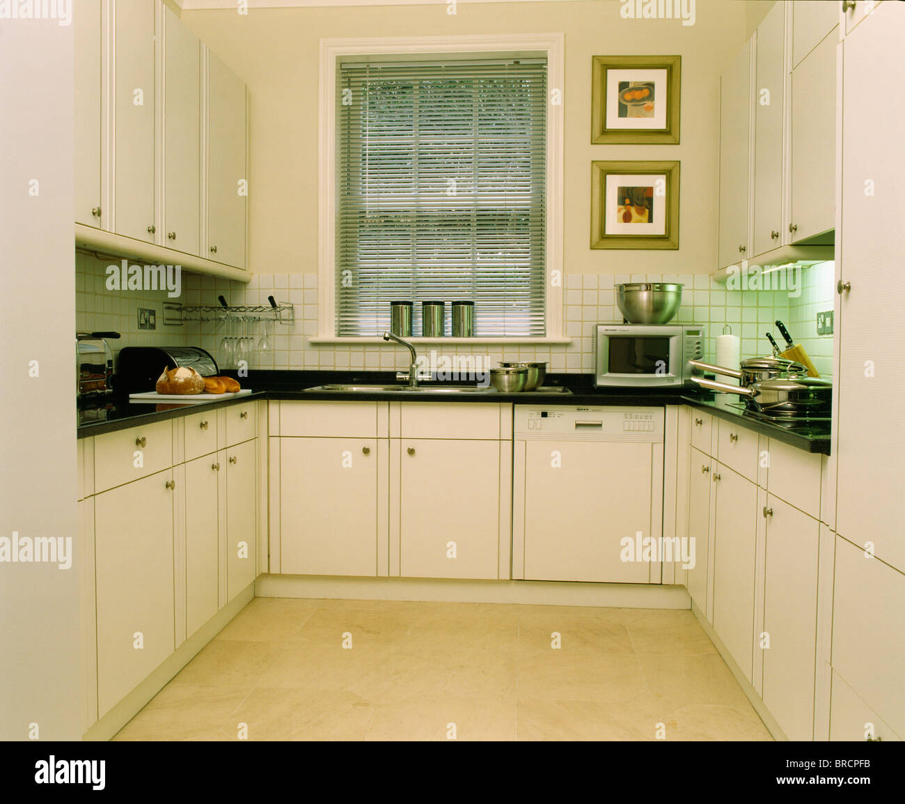 Tenda a veneziana sulla finestra sopra il lavabo e dotato di lavastoviglie  in piccola e moderna casa cittadina bianca cucina con granito nero piani di  lavoro Foto stock - Alamy