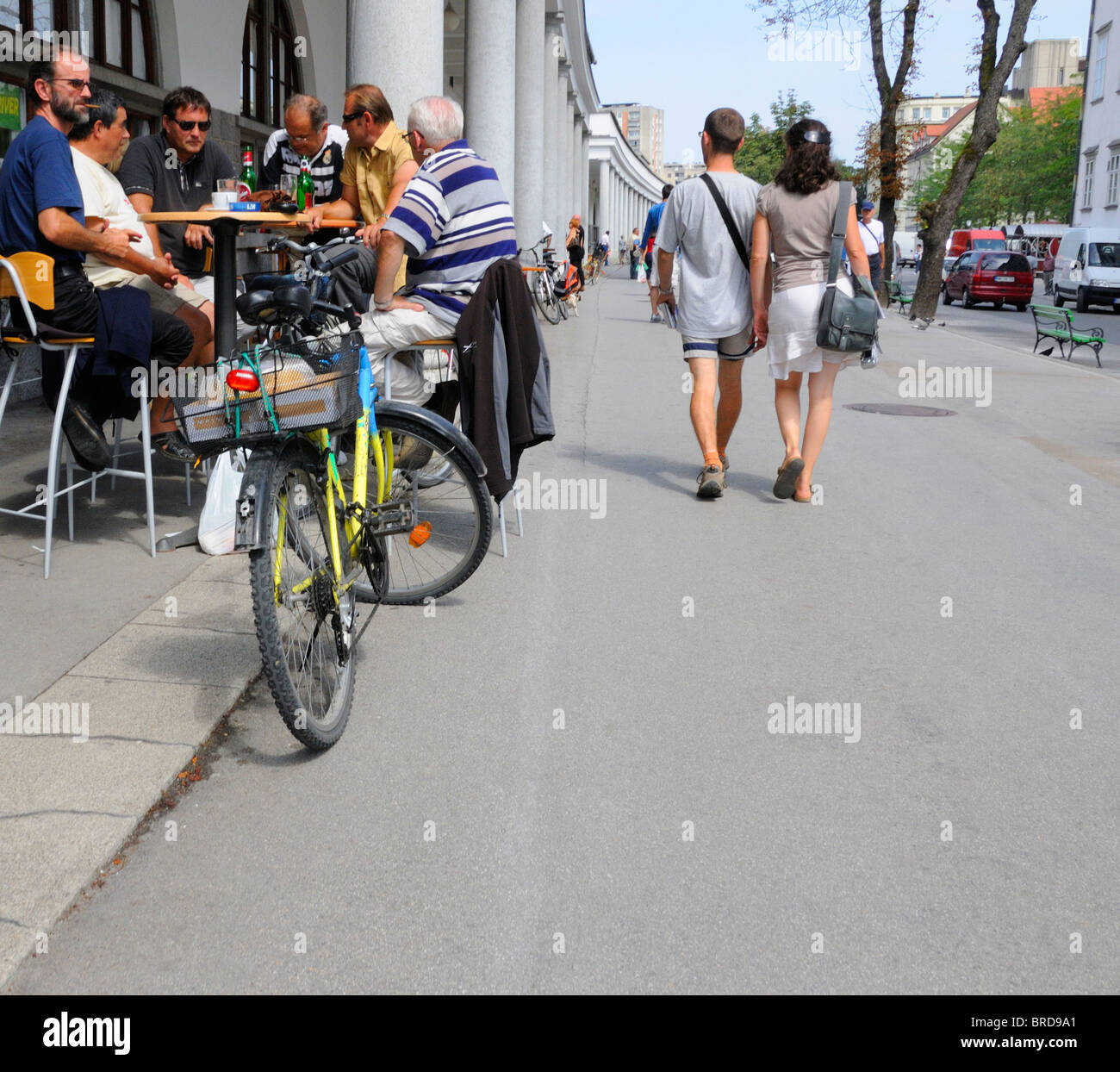 Lubiana, Slovenia. Giovane a piedi gli uomini passati al bar esterno tabella nel colonnato Plecnik Foto Stock