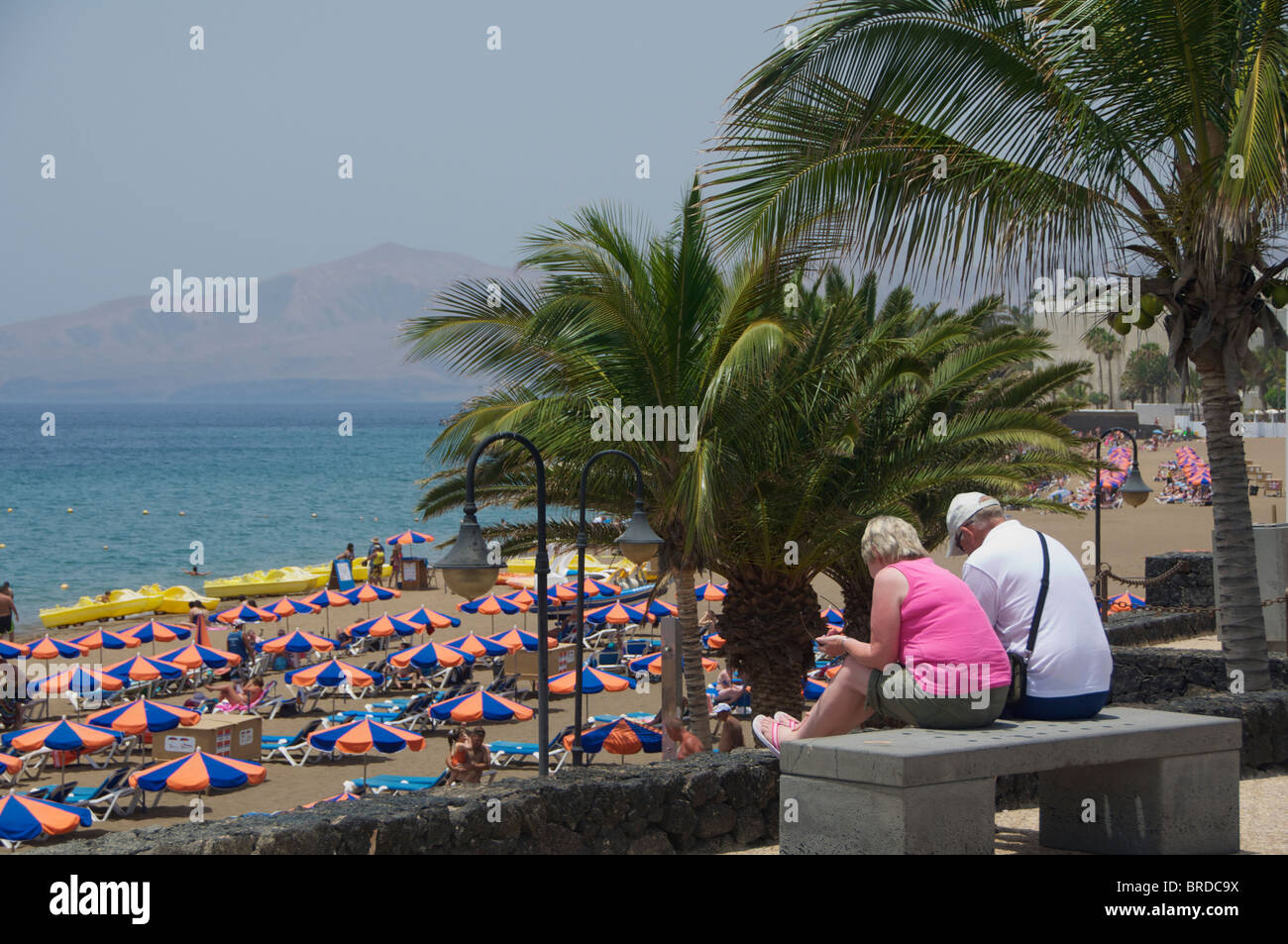 Una coppia di mezza età seduta vicino alla spiaggia di Puerto Del Carmen, Lanzarote, Isole Canarie Foto Stock