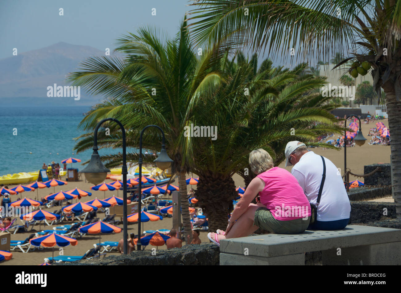 Una coppia di mezza età seduta vicino alla spiaggia di Puerto Del Carmen, Lanzarote, Isole Canarie Foto Stock