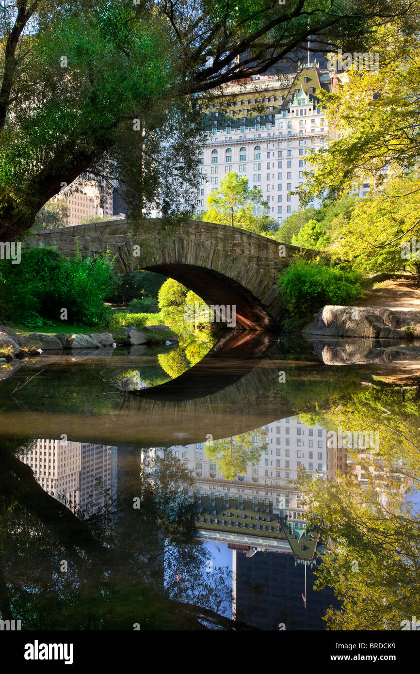 Ponte di pietra sul laghetto di Central Park con riflessioni del Plaza Hotel di New York City, Stati Uniti d'America Foto Stock