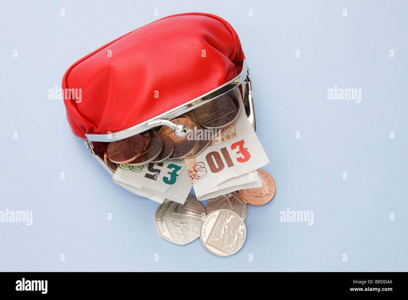 Studio, still life, Regno Unito, Europa. Red denaro borsa contenente dieci e cinque pound note con alcune monete fuoriuscita Foto Stock