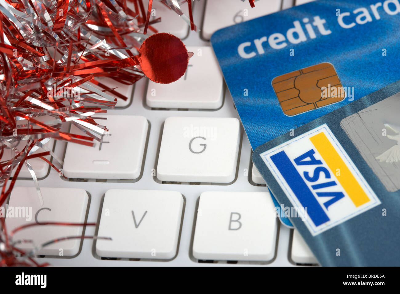Carte di credito sulla tastiera di un computer con orpelli natalizi decorazione xmas trascorrere la spesa di debito e denaro Foto Stock
