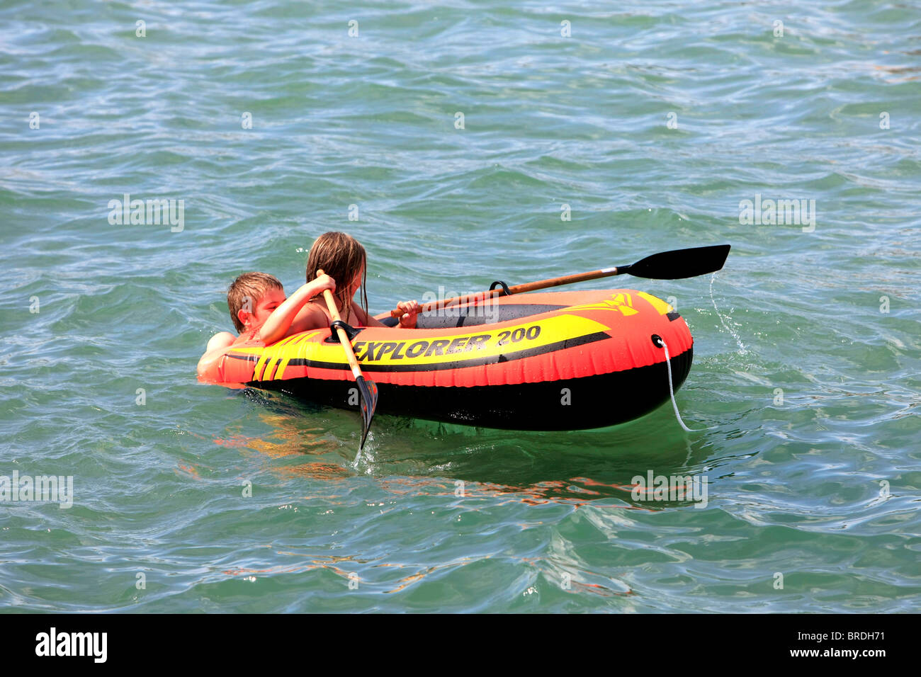 Fratello e Sorella di giocare con una gomma barca in mare a Weymouth Foto Stock