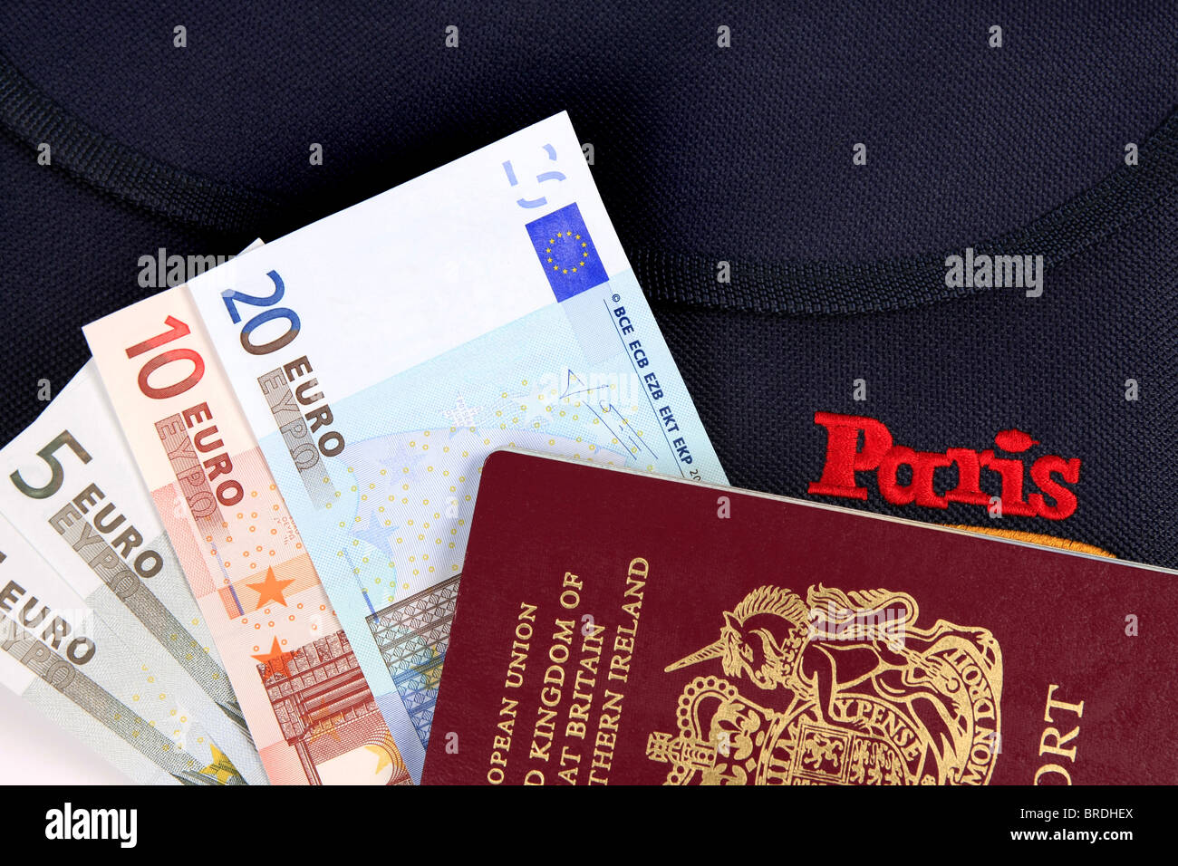 Euro denaro un passaporto britannico e una cartella la promozione di Parigi insieme contro uno sfondo bianco Foto Stock
